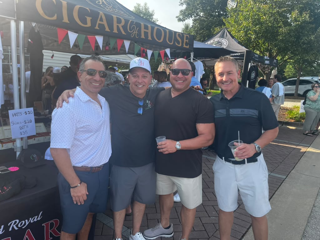 Guests gathered at the Cigar House tent on Third Street during the Old Town Italian Fest in Bloomingdale, with hats and shirts on display