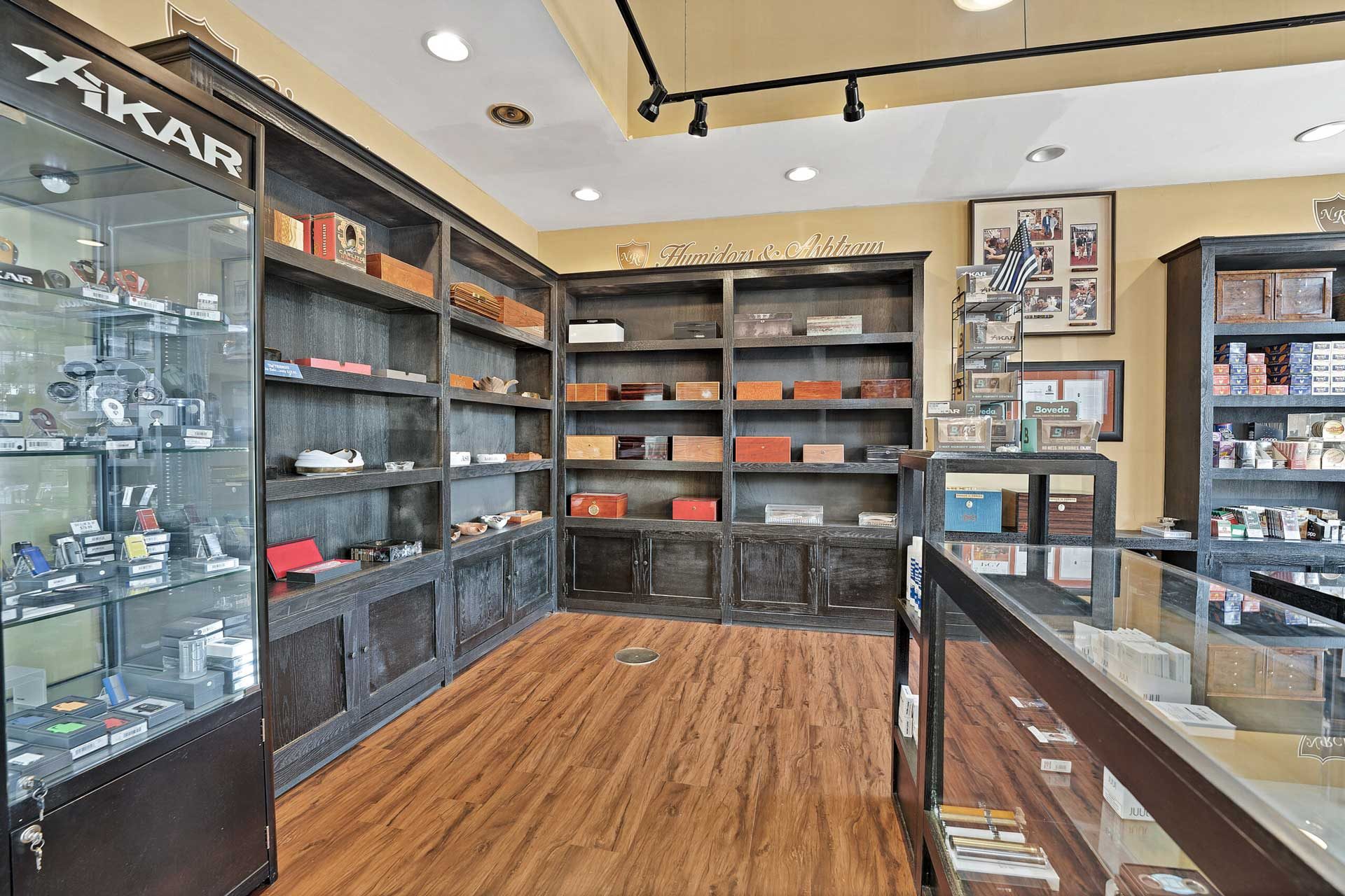 The humidors and ashtrays wall at Norwood Royal Cigars, dark shelving with desktop humidors, ashtrays and lighter cases