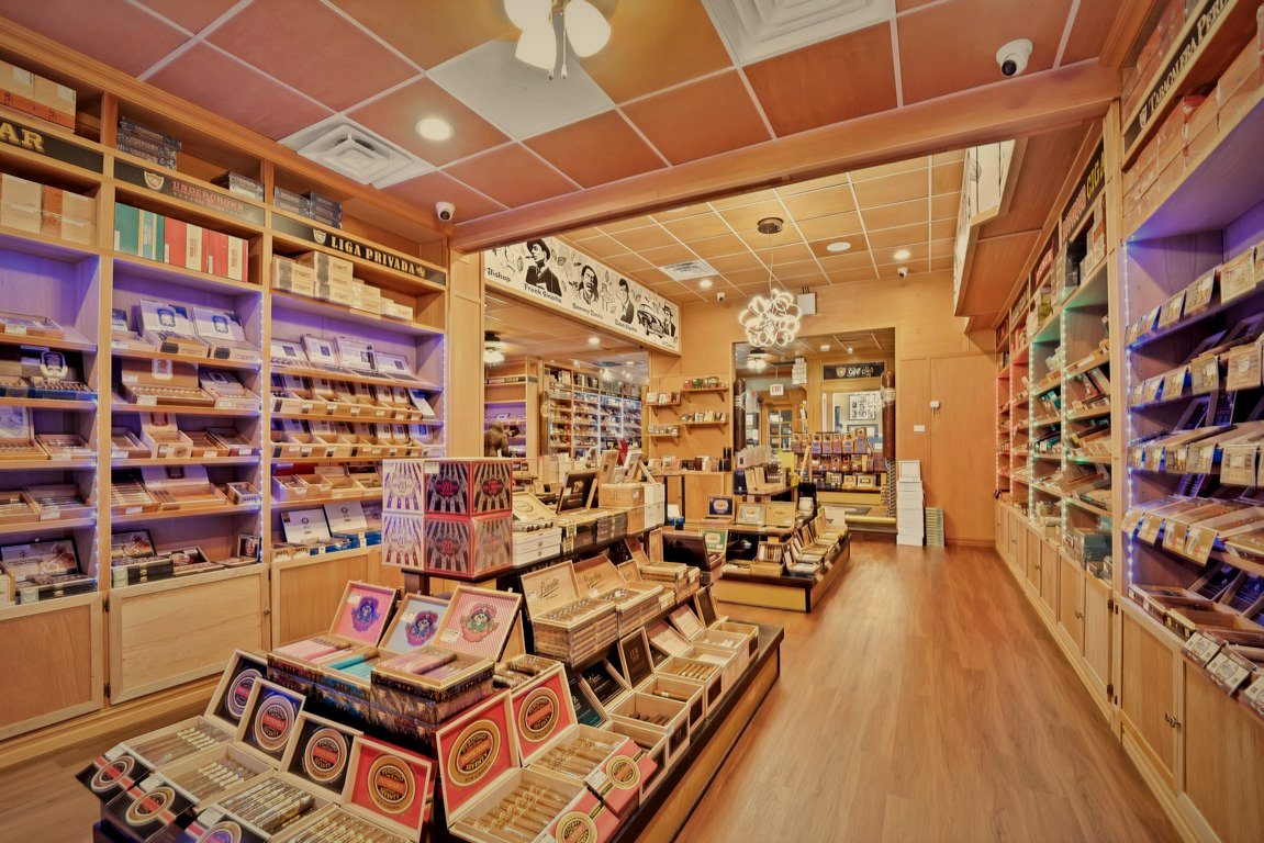 Backlit humidor shelving at Norwood Royal Cigars, boxes of premium cigars under violet accent lighting