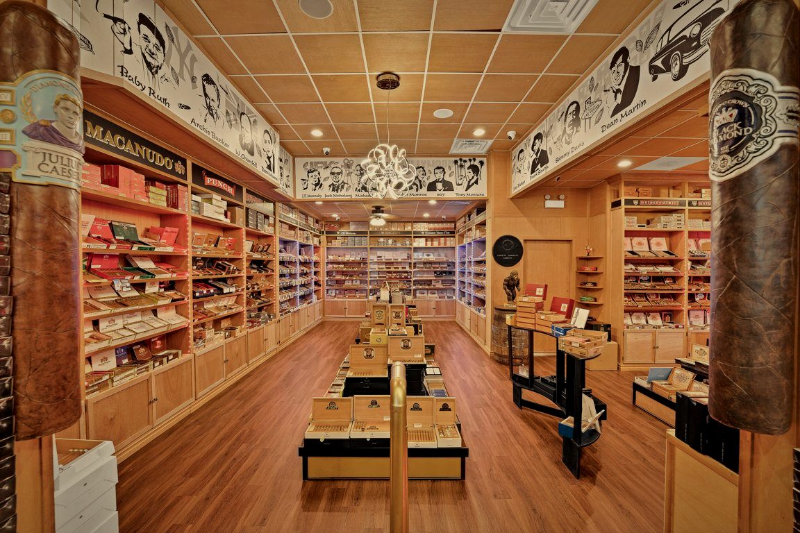 The walk-in humidor at Norwood Royal Cigars, shelves of premium cigars lining both walls beneath a hand-painted mural